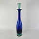 Flaske med prop 
af blåt klart 
glas, bund og 
prop i lysere 
glas fra serien 
Harlekin.
Producent ...