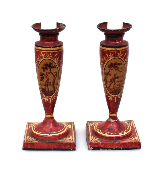 A pair of tin candle holders, red decorated with gildings