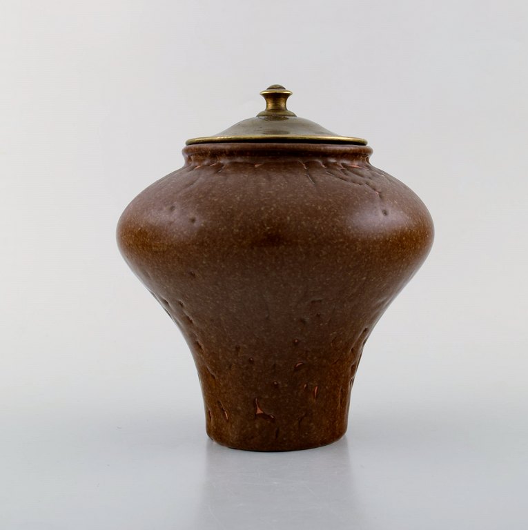 Patrick Nordström for Royal Copenhagen. Stoneware lidded vase decorated with 
brown and sand colored glaze. Bronze lid decorated with ornaments. Ca. 1920.