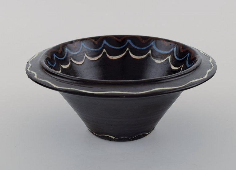 Kähler, Denmark. Bowl in black glazed ceramics with blue and white waves along 
the edge. 1930s / 40