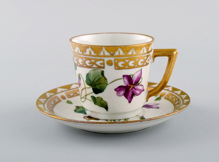 Royal Copenhagen kaffekop med underkop i håndmalet porcelæn med gulddekoration 
og blomster. Flora danica stil, 1960