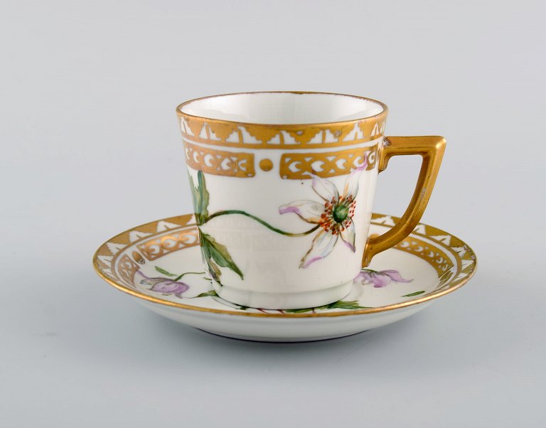 Royal Copenhagen kaffekop med underkop i håndmalet porcelæn med gulddekoration 
og blomster. Flora danica stil, 1960