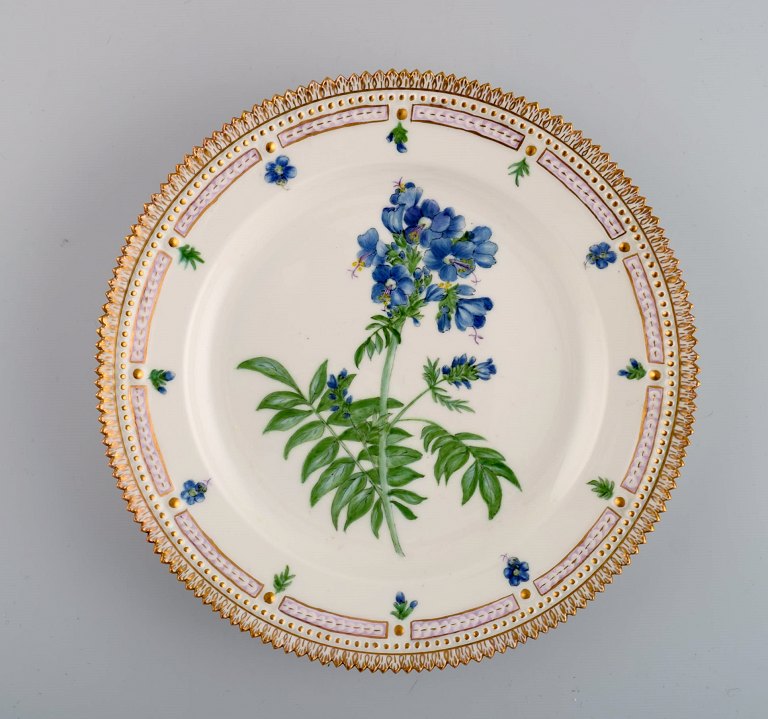 Royal Copenhagen Flora Danica tallerken i håndmalet porcelæn med blomster og 
gulddekoration. Dateret 1952.
